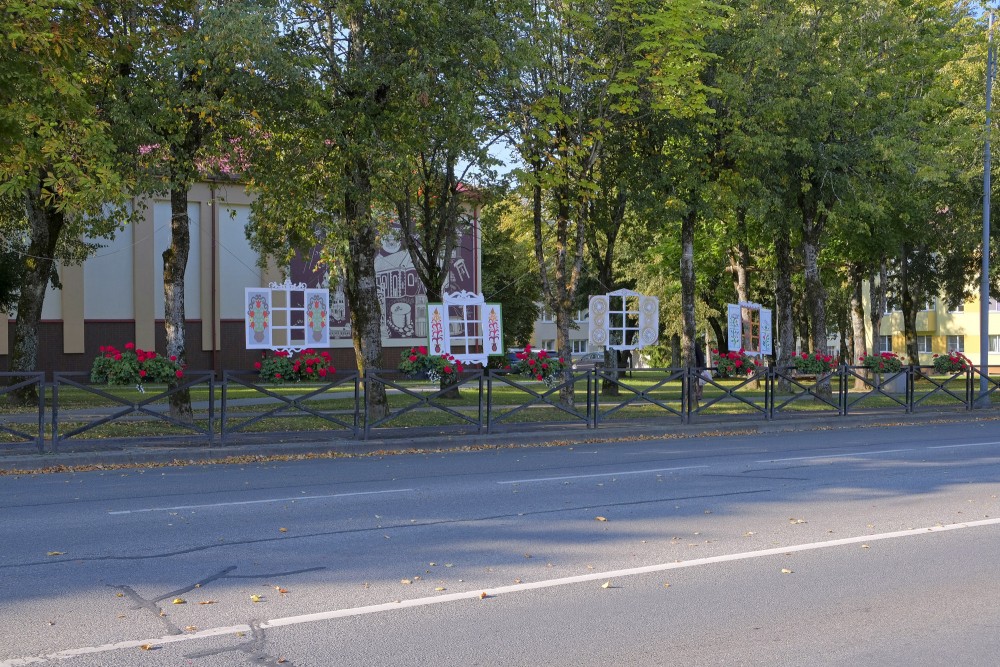 Dekoratīvi pilsētvides logu stendi gar koku aleju Skuodā