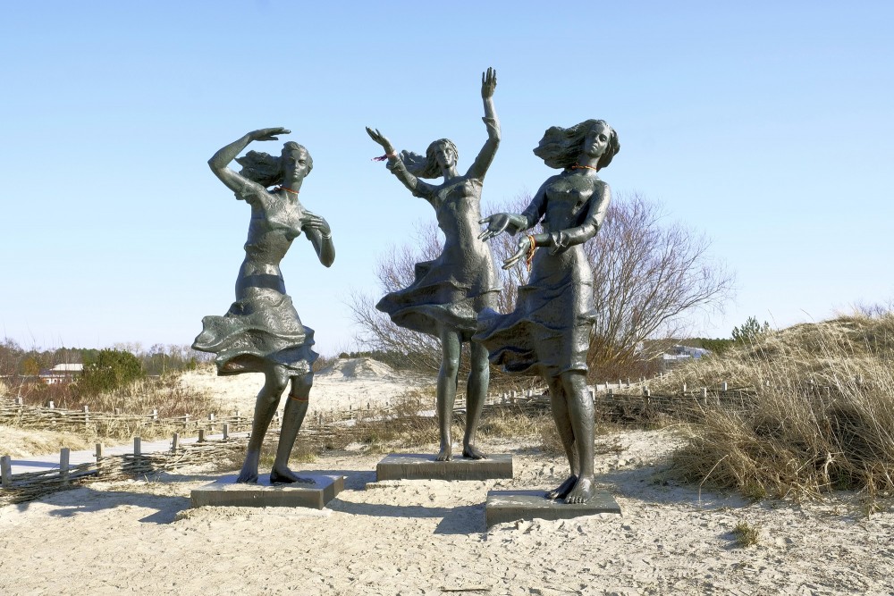 Skulptūra "Zvejnieka meitas" smilšu kāpās ar zilām debesīm