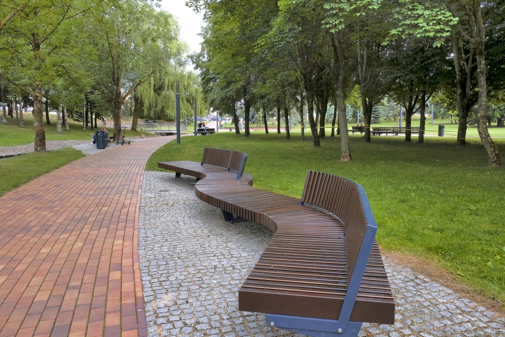 Modern wooden park bench and paved path view in Marijampole Poetry Park