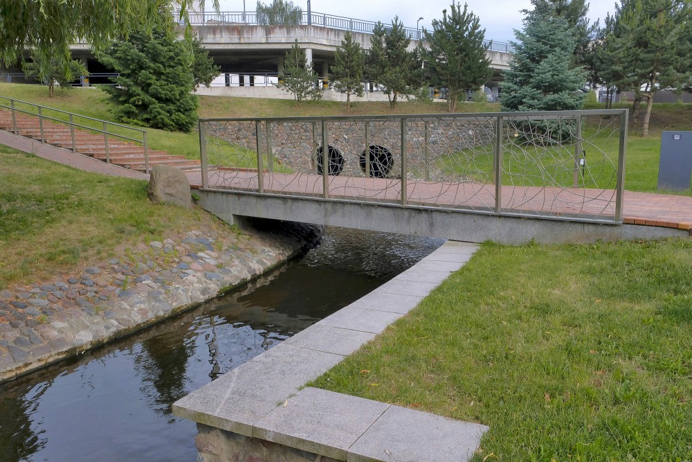 Pedestrian bridge over stone canal in Marijampole Poetry Park