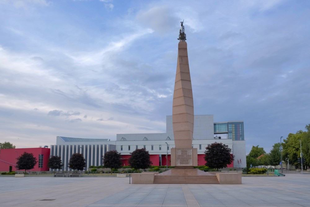 Monument to Nation and Language in Marijampole with cultural building background