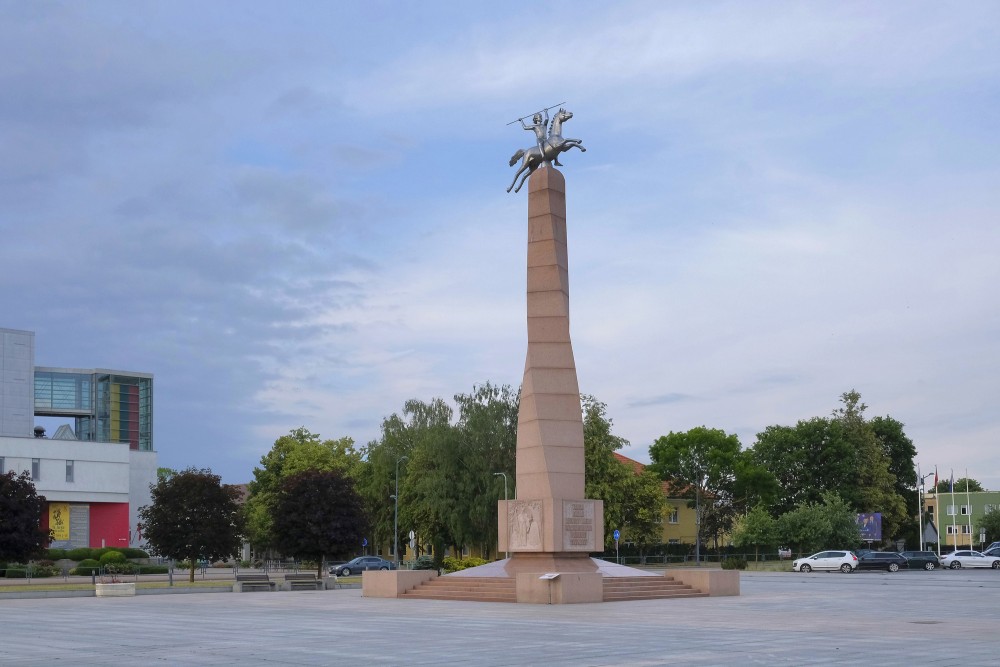 Monument to Nation and Language in Marijampole square with green trees background