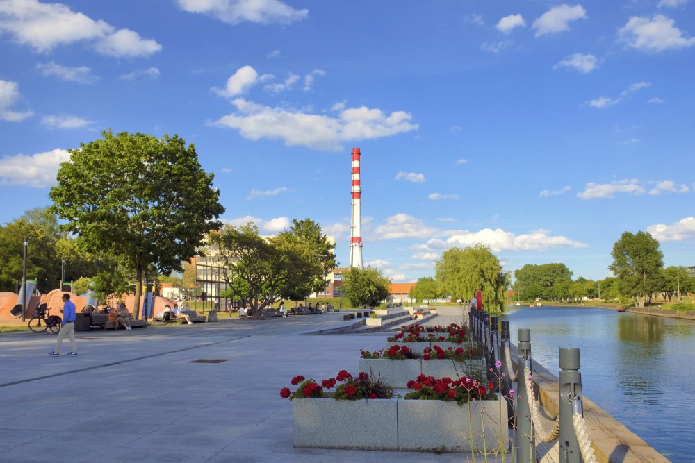 Danes river promenade with flower boxes, playground and a view of an industrial chimney